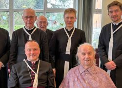 Eine Gruppe von Geistlichen feiert den 90. Geburtstag eines Mannes im Stift Reichersberg.