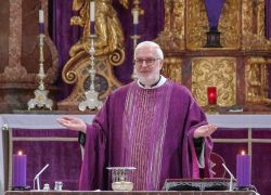 Ein Priester in violetter Robe zelebriert eine Messe im Stift Reichersberg vor einem reich verzierten Altar.
