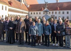 Eine Gruppe von Besuchern posiert vor dem historischen Stift Reichersberg an einem sonnigen Tag.