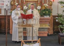 Zwei Priester zelebrieren die Altarweihe in der Kirche von Pfarre Pitten, neben einem festlich geschmückten Weihnachtsbaum.