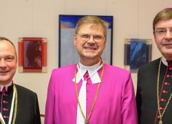 Drei Geistliche stehen in festlicher Kleidung bei der Abtbenediktion im Stift St. Florian, ein Ereignis ähnlich dem im Stift Reichersberg.