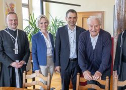 Eine Gruppe von sechs Personen steht lächelnd zusammen im Stift Reichersberg während eines Besuchs aus Bayern.