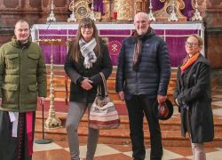 Eine Gruppe von vier Personen steht vor dem Altar im Stift Reichersberg während eines Besuchs im März 2023.