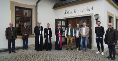Das Team des Stifts-Bräustüberls posiert vor dem Eingang des Stift Reichersberg für ein Gruppenfoto.