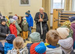 Viele Kinder umringen einen älteren Mann im Stift Reichersberg, um seinen 100. Geburtstag zu feiern.