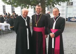 Geistliche versammeln sich im Innenhof von Stift Reichersberg zur Abtbenediktion, während Gäste an Tischen sitzen.