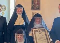 Eine Gruppe von Geistlichen feiert den 80. Geburtstag von Sr. Rita im Kloster Stift Reichersberg mit einer Urkunde.