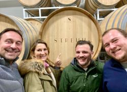 Eine fröhliche Gruppe posiert vor einem Weinfass im Stift Reichersberg.