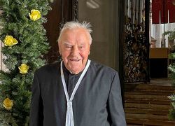 Ein älterer Herr steht lächelnd vor dem festlich geschmückten Eingang des Stift Reichersberg zu seinem 99. Geburtstag.