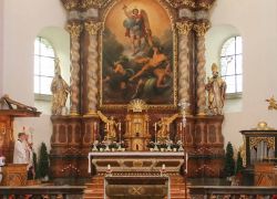 Priester versammeln sich vor dem Altar des Stift Reichersberg, umgeben von prächtigen Gemälden und Skulpturen.