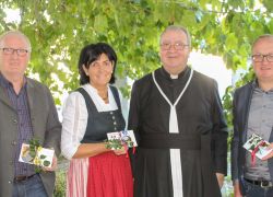 Eine Gruppe von vier Personen posiert lächelnd unter einem Baum bei einer Feier im Stift Reichersberg.