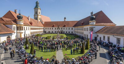 Motorradfahrer versammeln sich im Innenhof des Stift Reichersberg zur Bikerwallfahrt am 27.04.2025 bei strahlendem Sonnenschein.