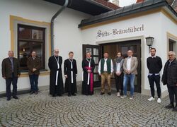 Das Team des Stifts-Bräustüberls posiert vor dem Eingang des Stift Reichersberg für ein Gruppenfoto.